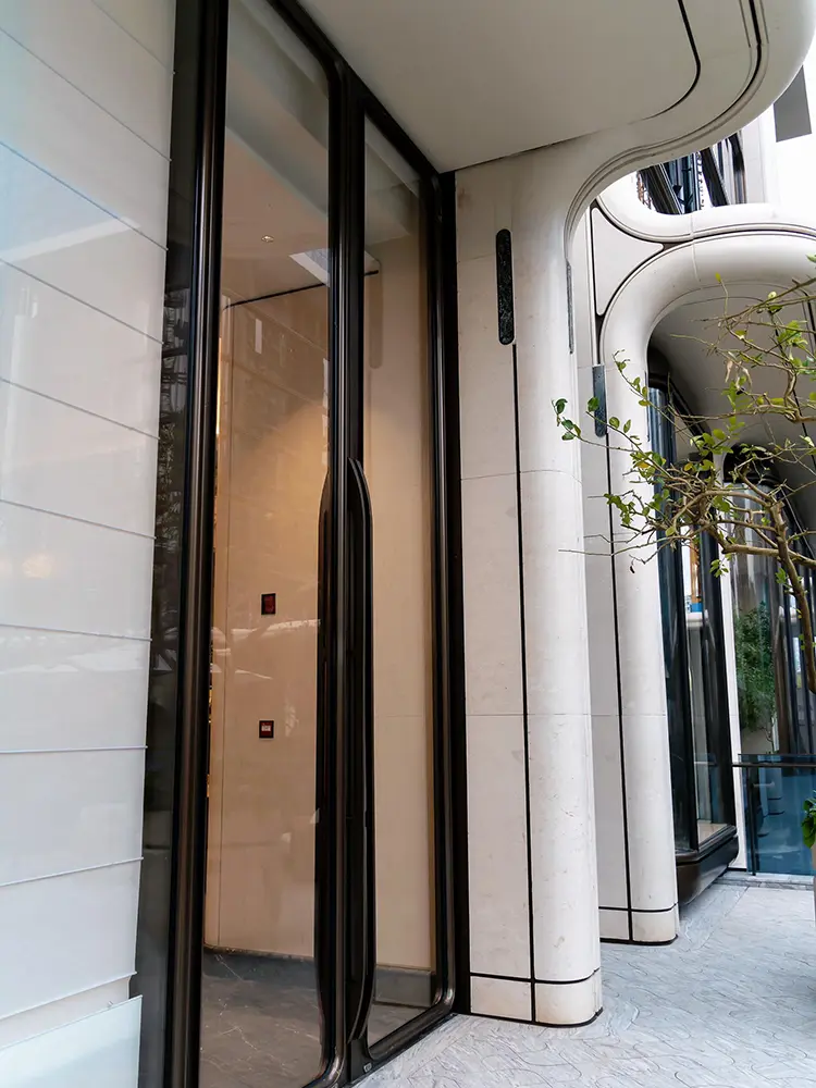 Home Rounded white aluminum entrance surround beside glass doors and overhead cladding
