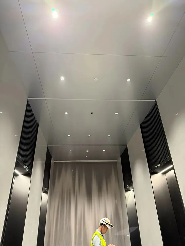 Clip-In vs Lay-In Metal Ceilings: Access, Fit and Buying Checks Metal ceiling panels and recessed lights in an interior corridor during finishing