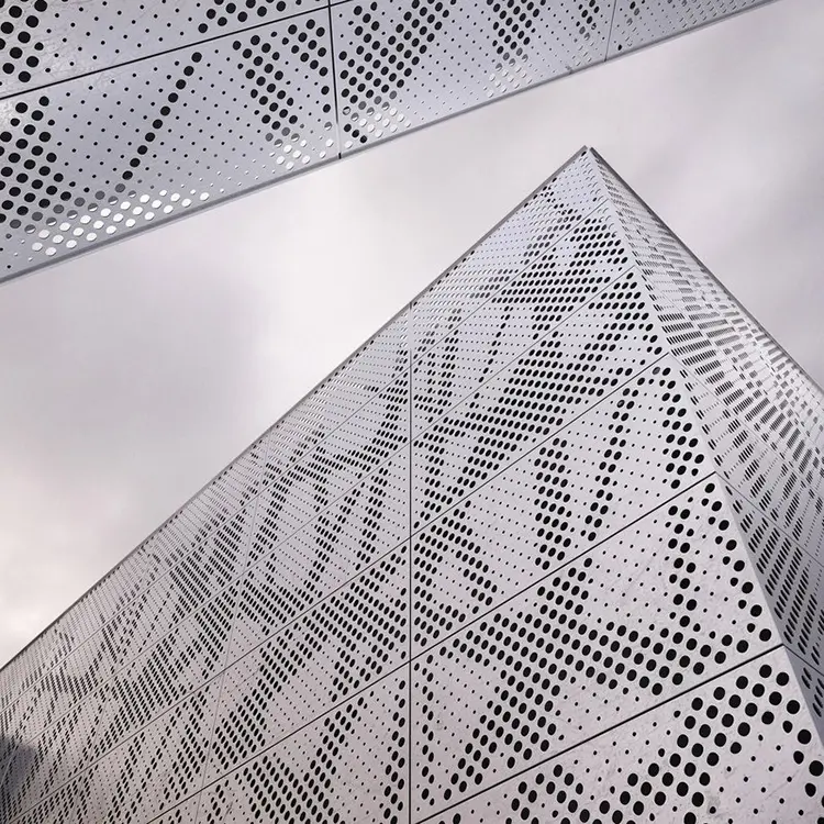 Laser Cutting vs Punching Aluminum Panels: What to Choose Large aluminum facade using circular openings to carry a pattern across panel joints